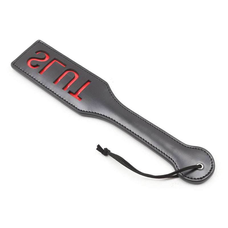 Spanking Fun SLUT Paddle i sort PVC med rødt cut-out tekst, 32x6 cm, let og elegant til leg og nydelse.